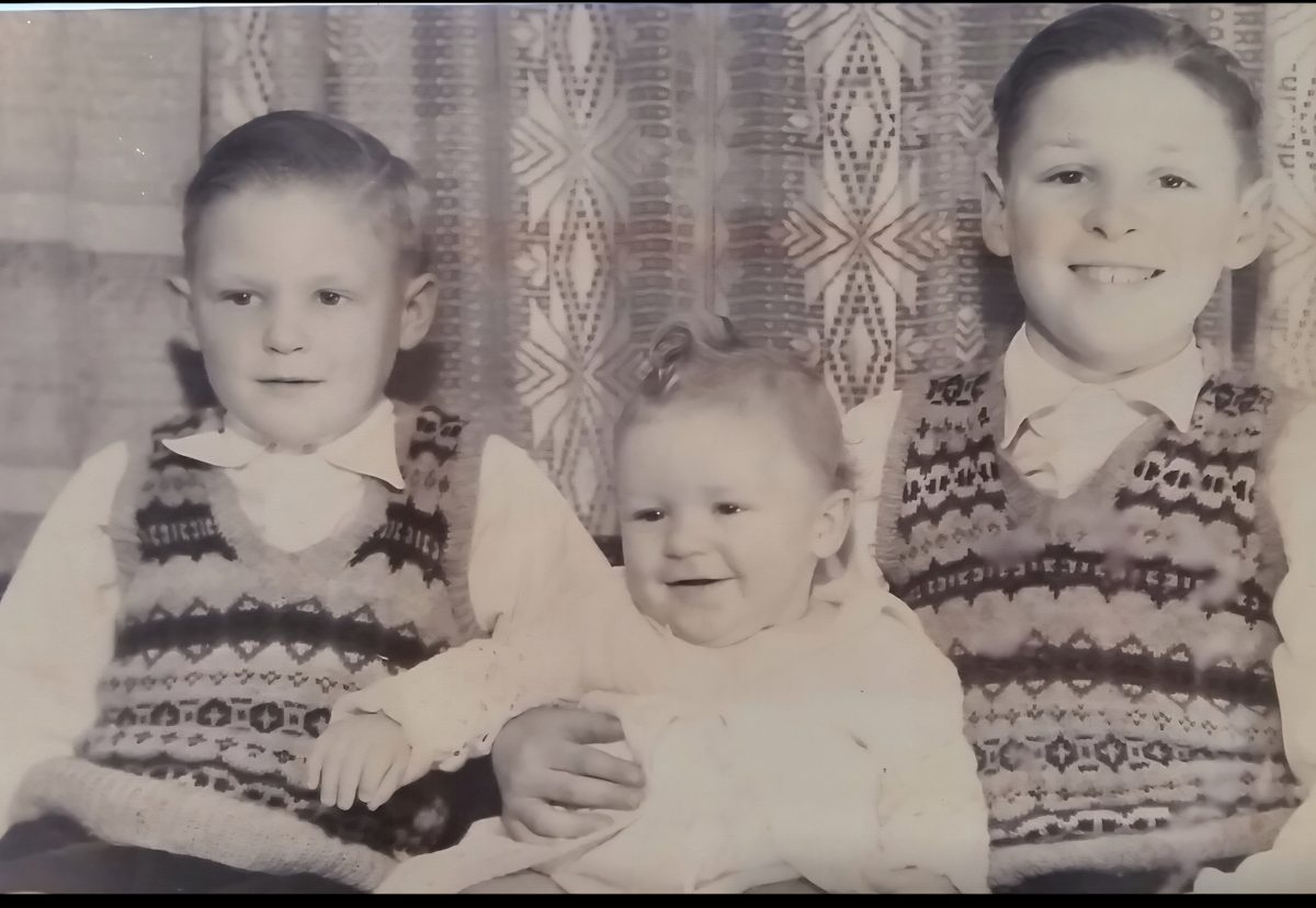 A faded black and white print of three brothers